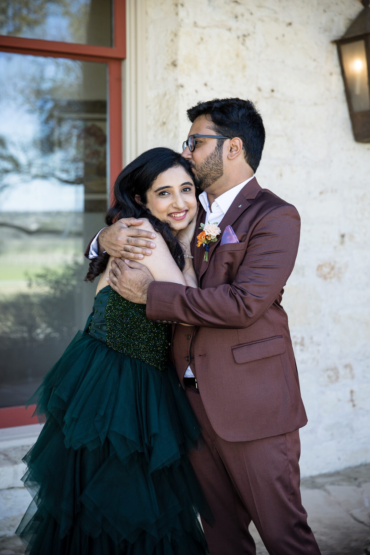 A couple in a tender first-look moment — groom kissing bride's cheek at Garey House