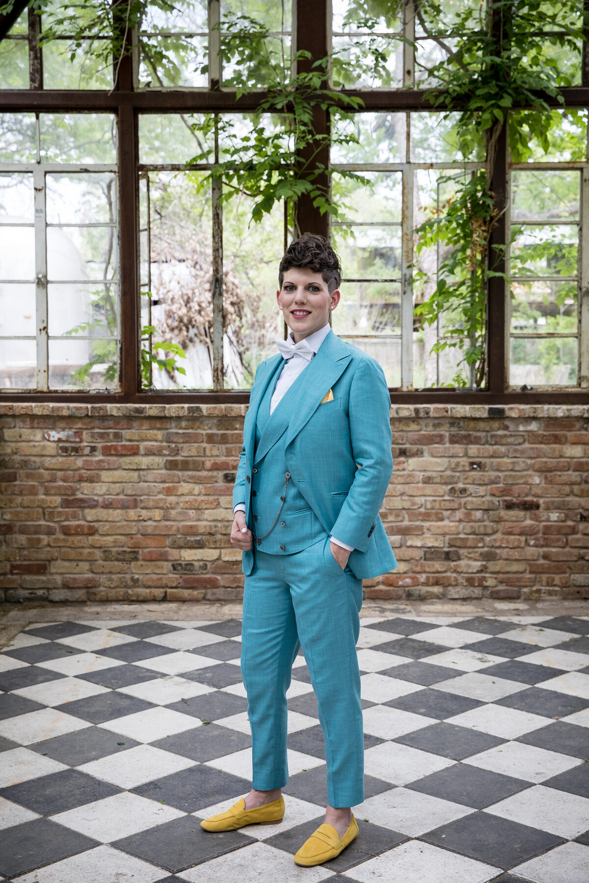 Queer couple in a teal three-piece suit and yellow loafers, photographed at Sekrit Theater in East Austin — a queer-affirming wedding venue