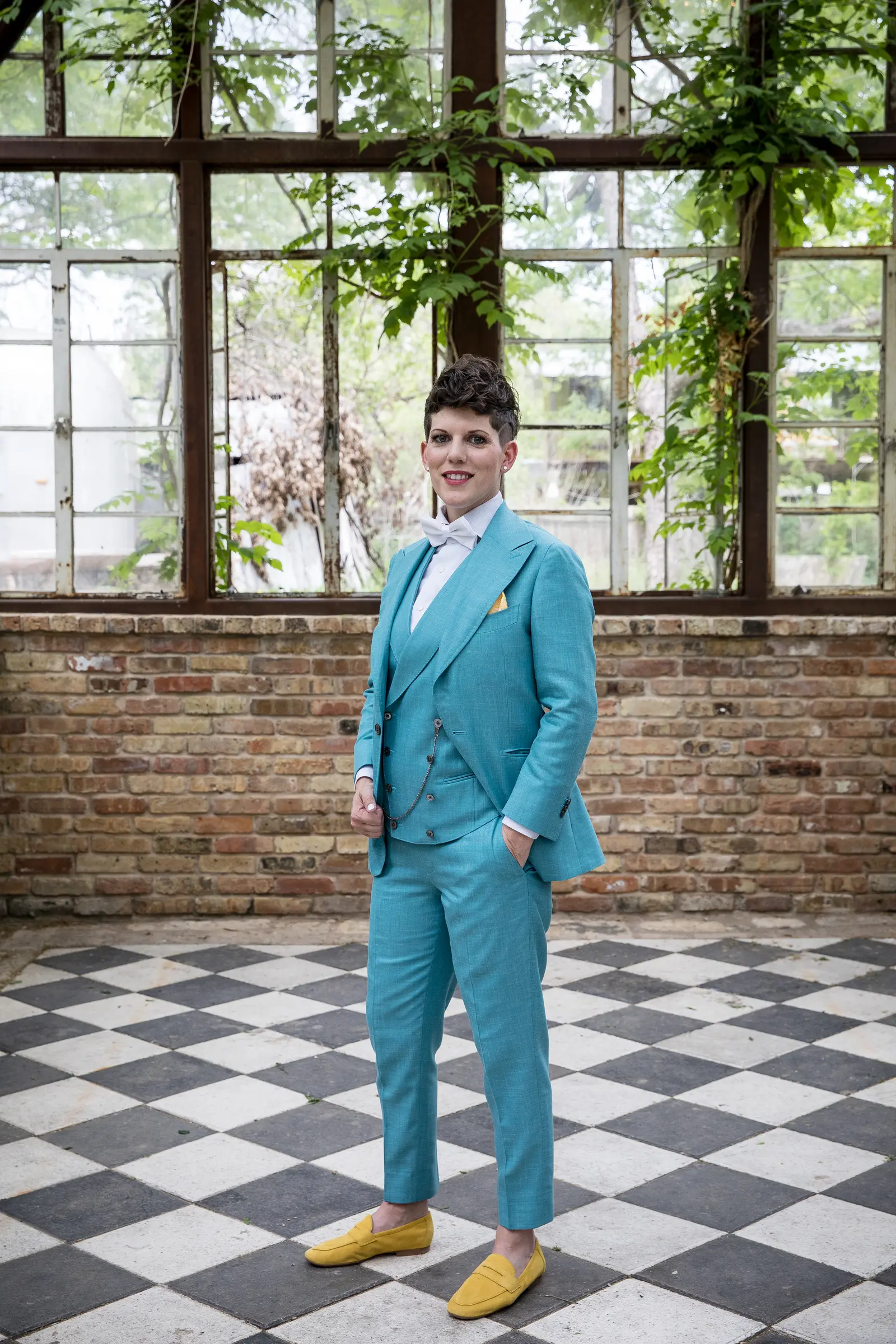 Queer couple in a teal three-piece suit and yellow loafers, photographed at Sekrit Theater in East Austin — a queer-affirming wedding venue
