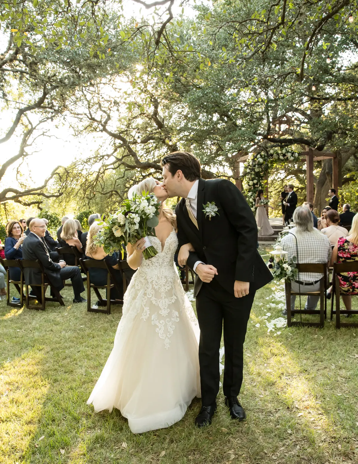 A couple sharing a recessional kiss in soft golden-hour light under live oak trees — a wedding photographer's ability to work in this light is what separates pros