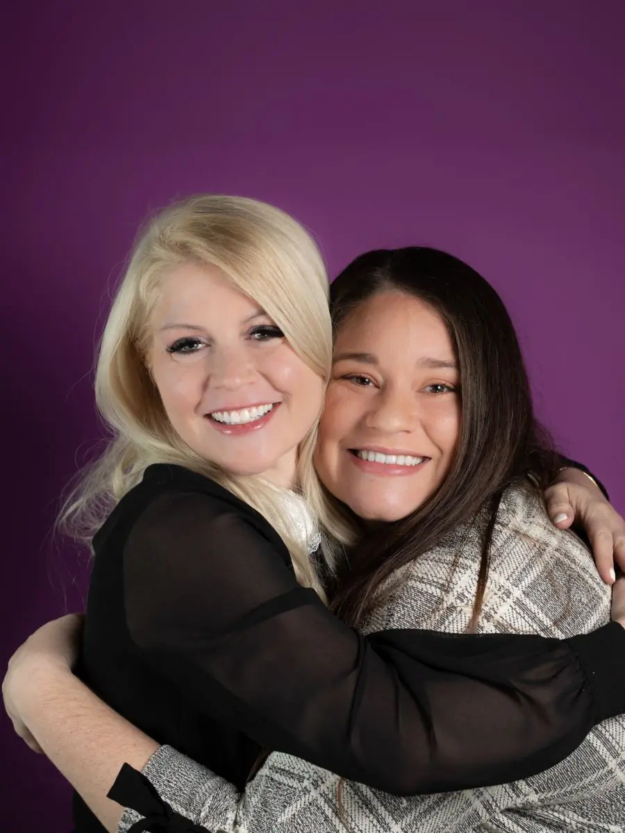 two women hugging, purple studio portrait