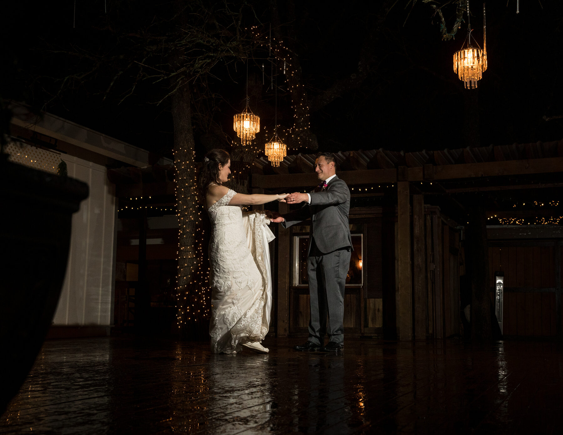 Couple slow-dancing under hanging chandeliers at night