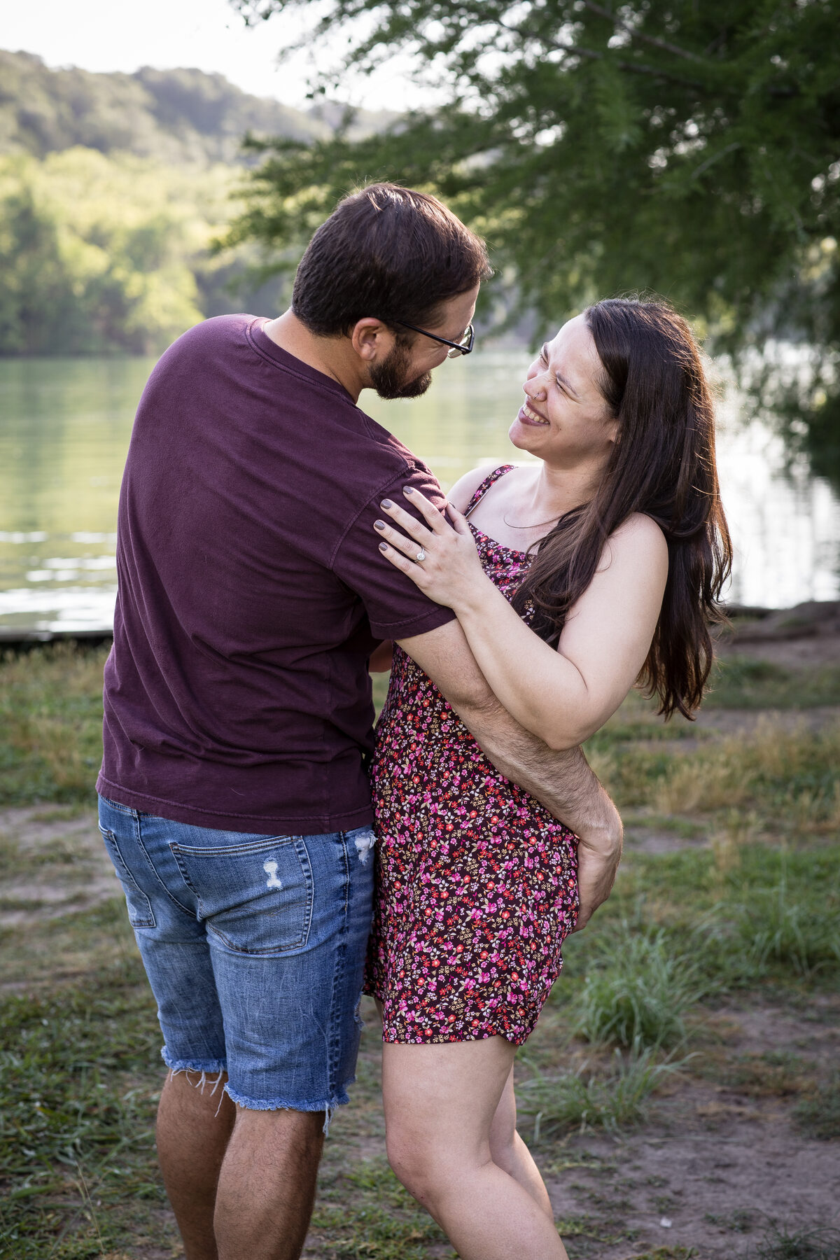 Engagement couple laughing by Austin river