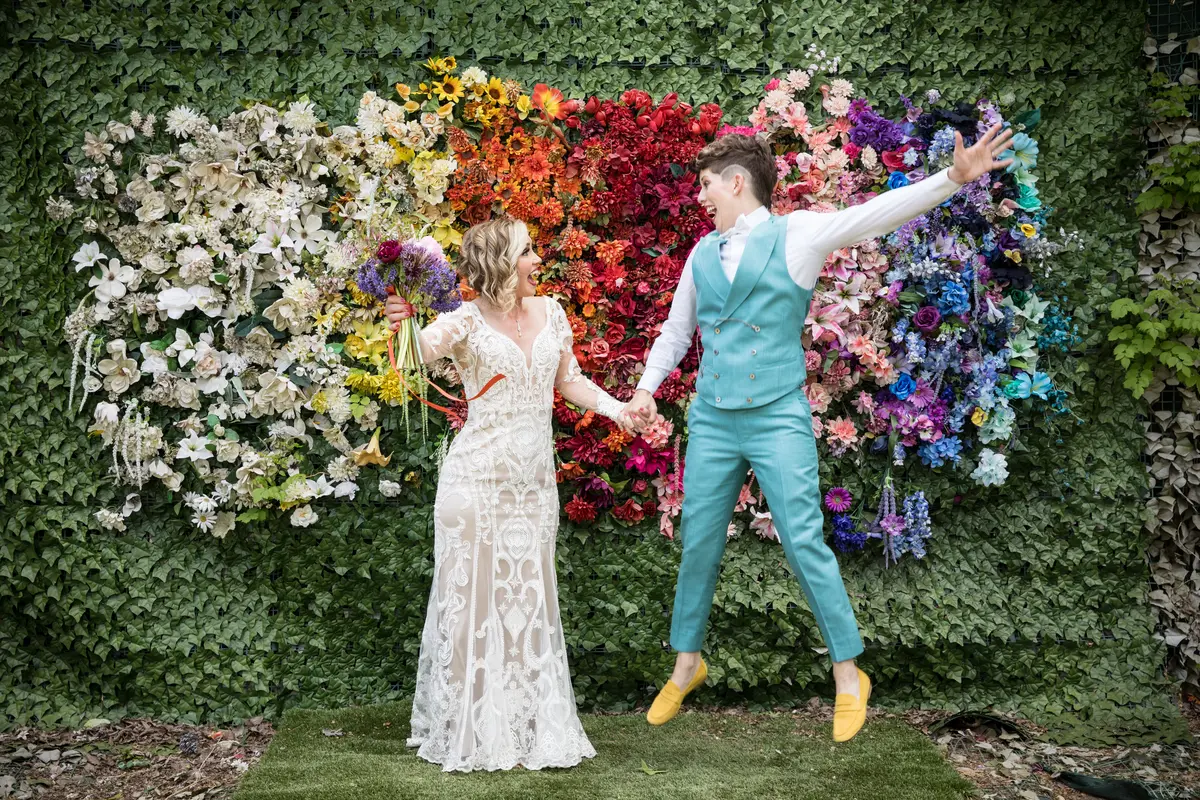 Couple in front of rainbow flower wall