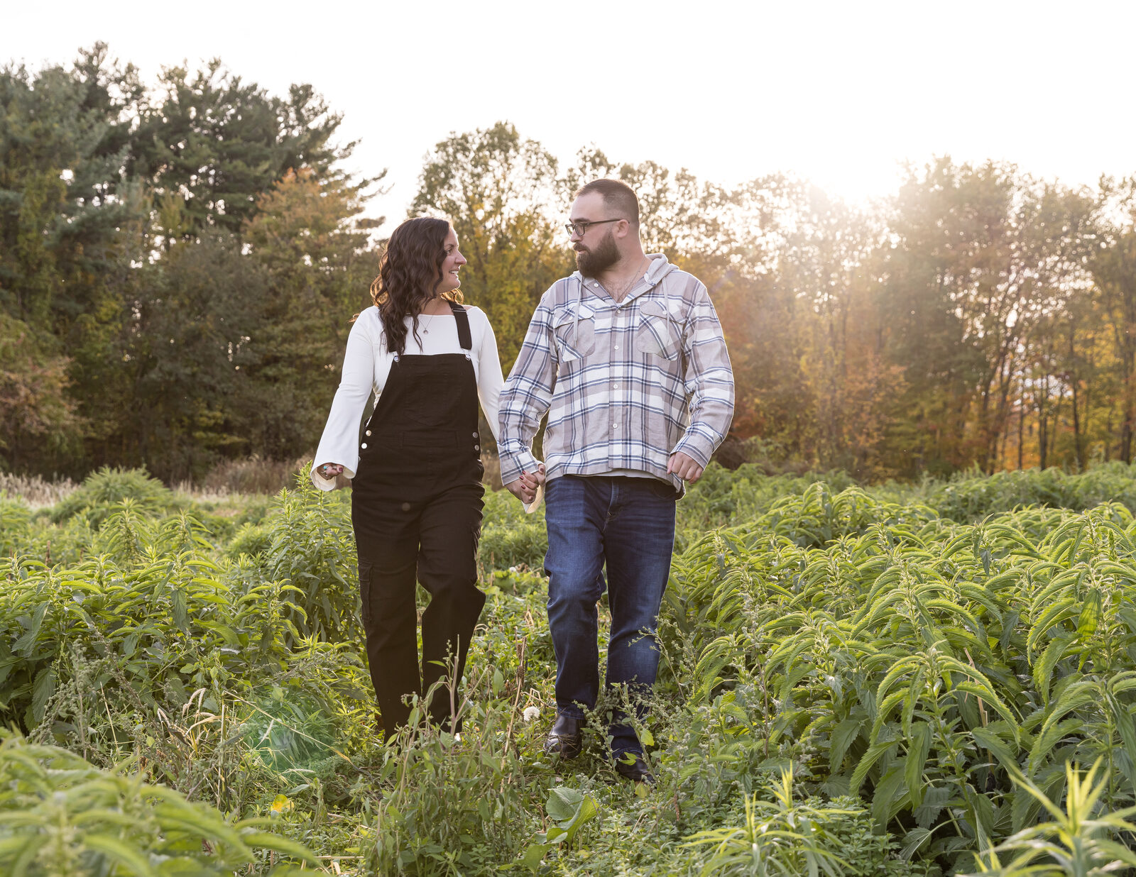 Couple walking through a sunlit autumn field at golden hour