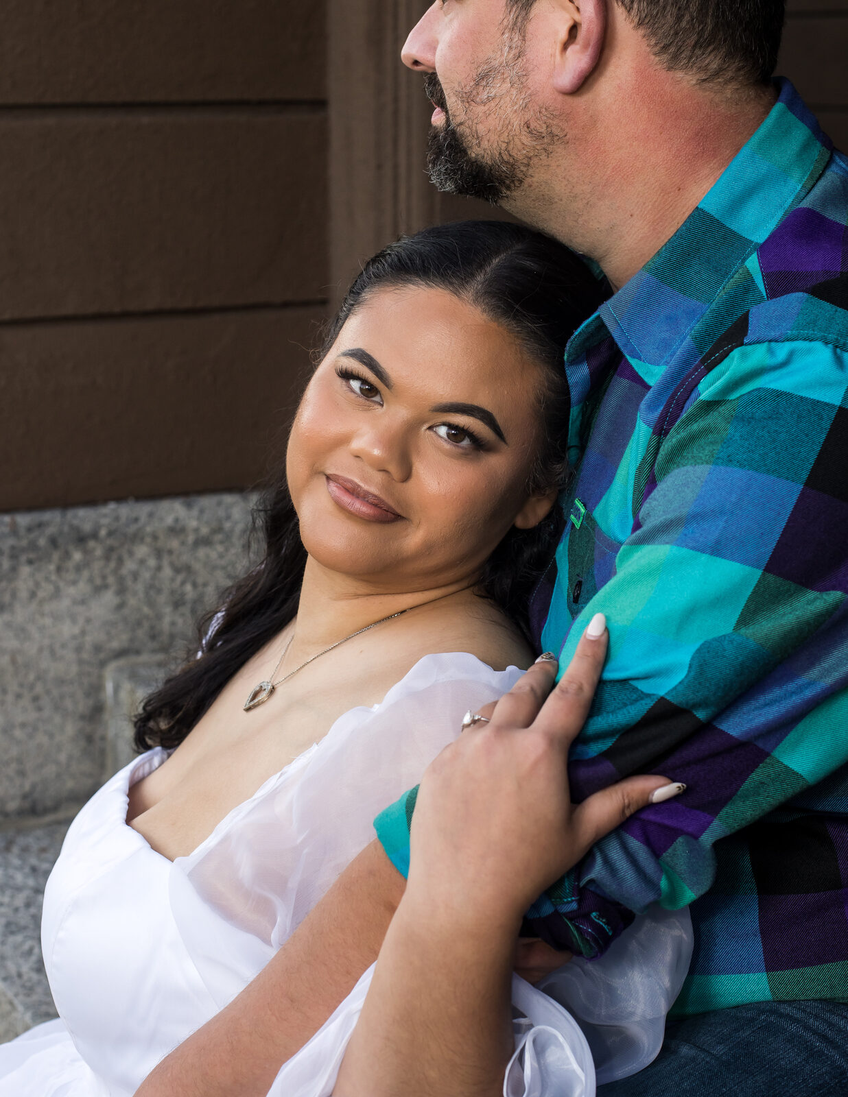 Engagement portrait of a couple against a stone wall