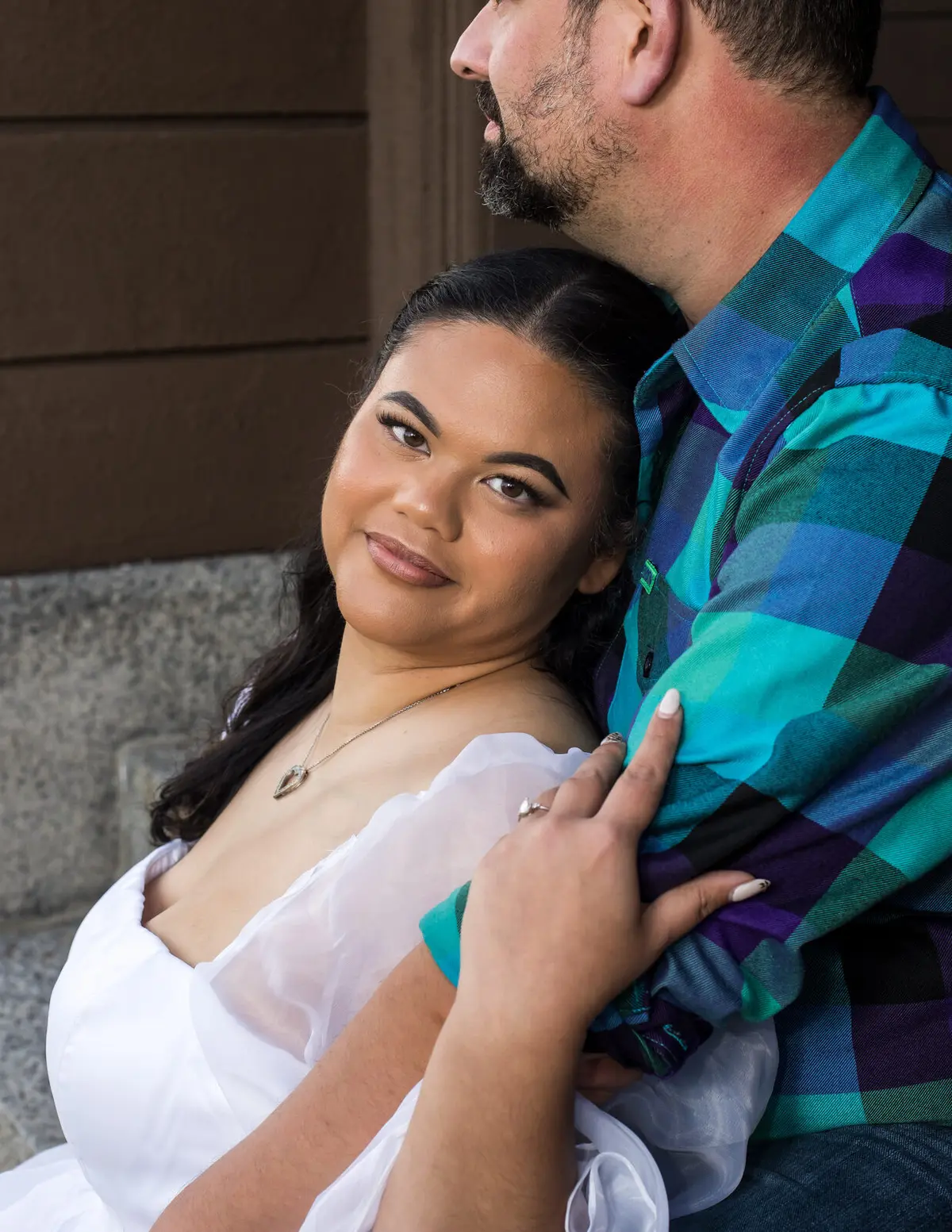 Engagement portrait of a couple against a stone wall