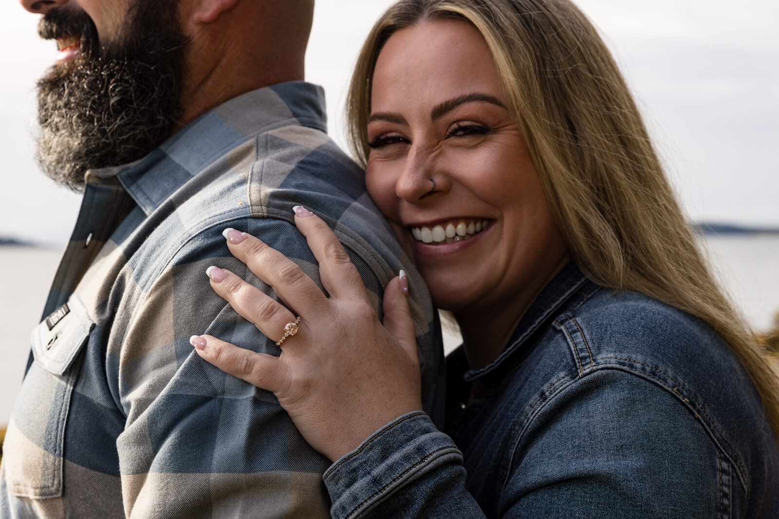 Smiling couple embracing with the engagement ring on display