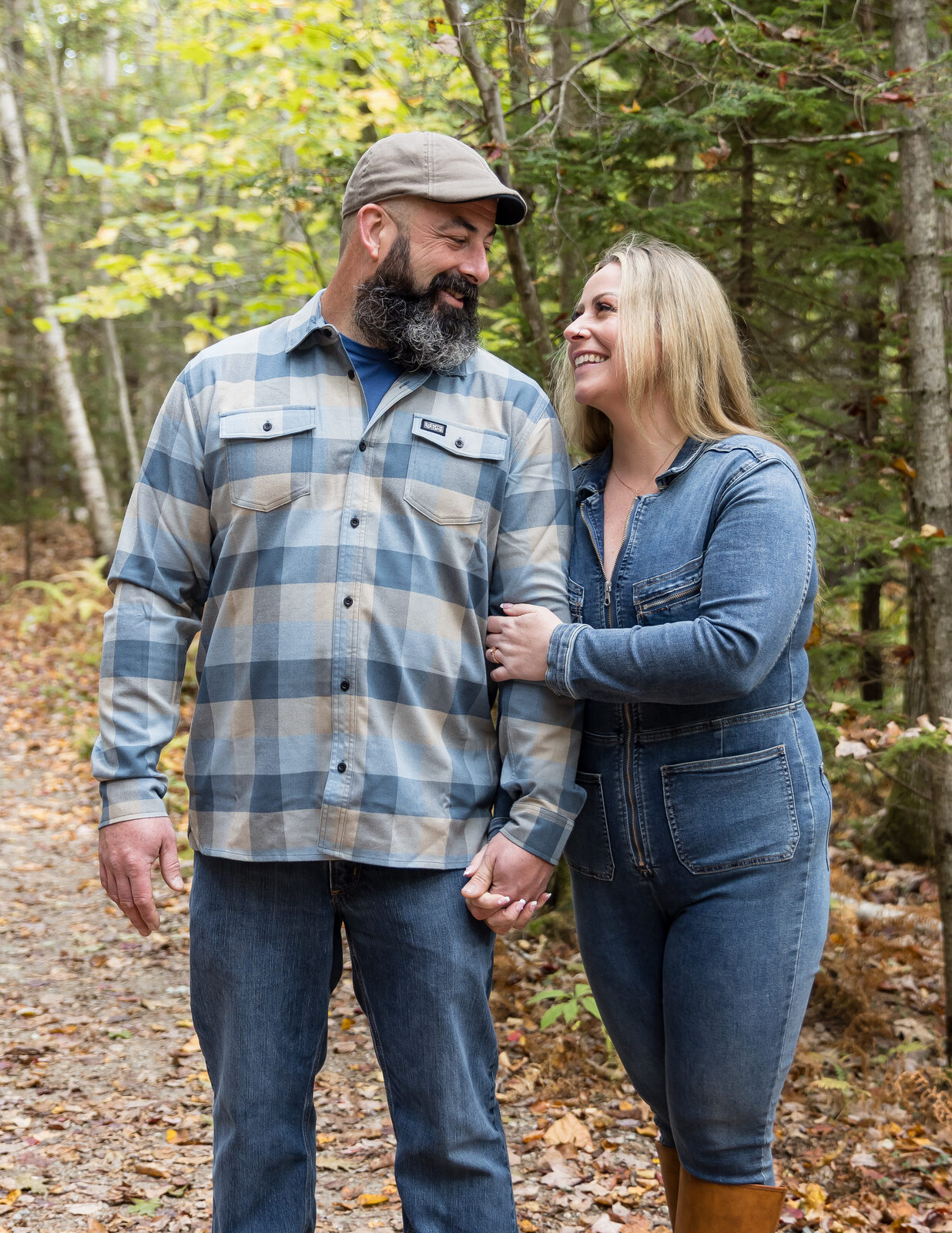 Couple holding hands and laughing on a wooded autumn trail