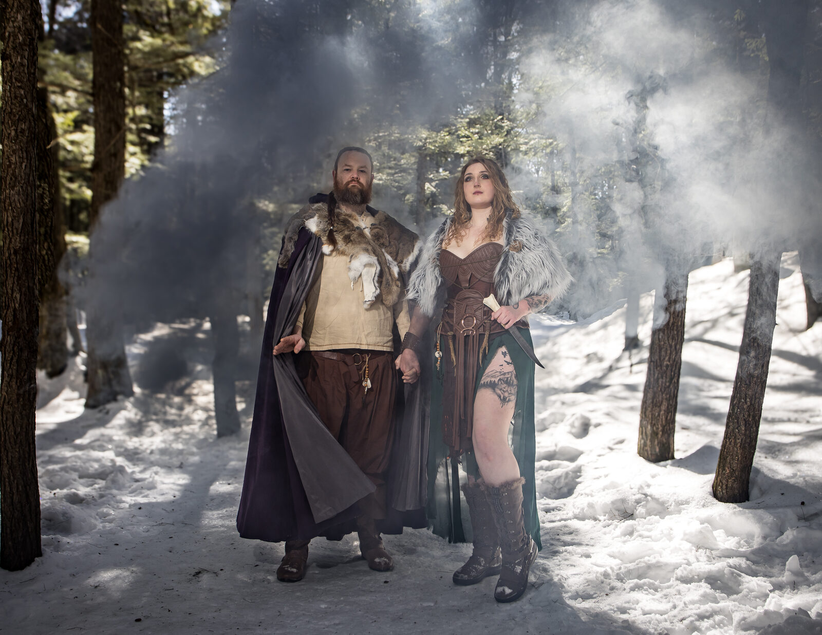 Couple setting off a purple smoke bomb at a Viking forest engagement session