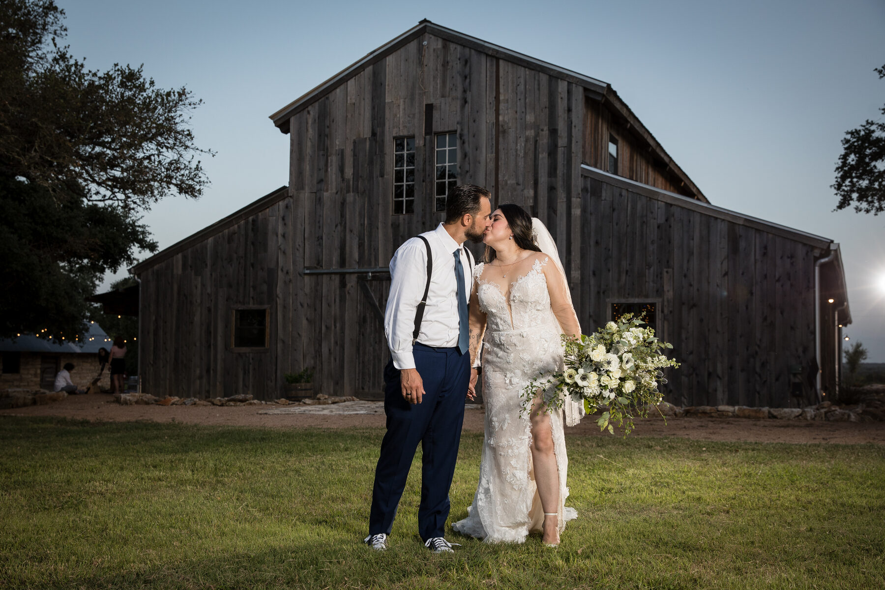 Couple kiss in front of rustic Texas barn at dusk