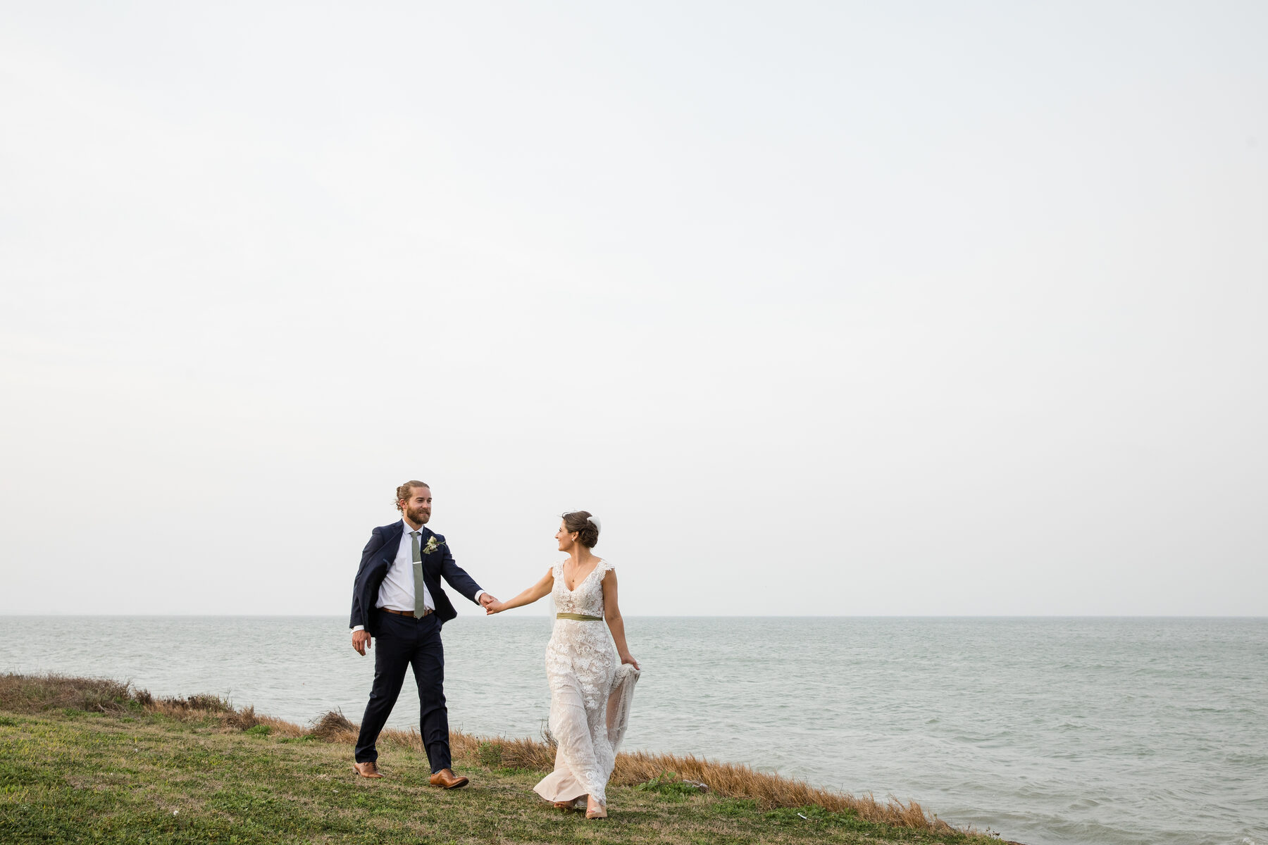 Couple holding hands along moody coastline