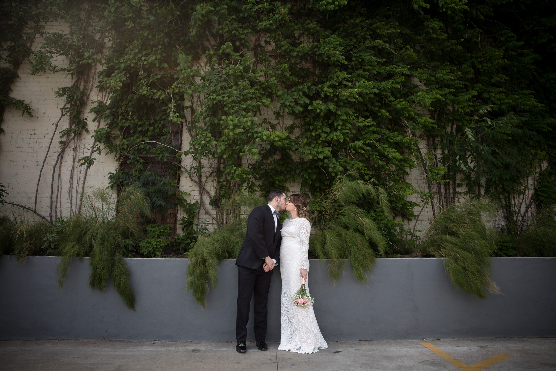 Couple kissing against ivy-covered Austin wall