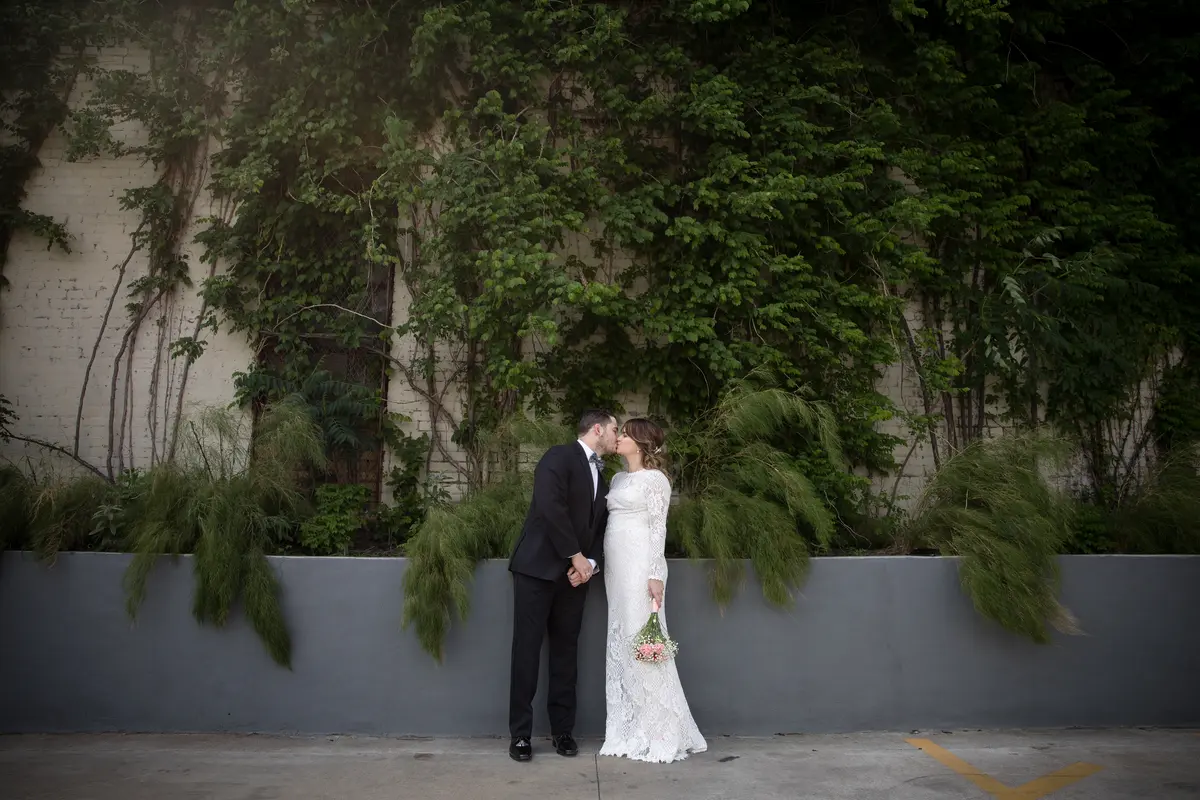 Couple kissing against ivy-covered Austin wall