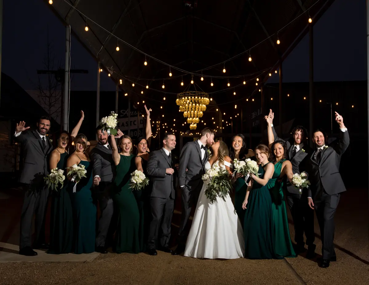 Wedding party cheering under string lights at night