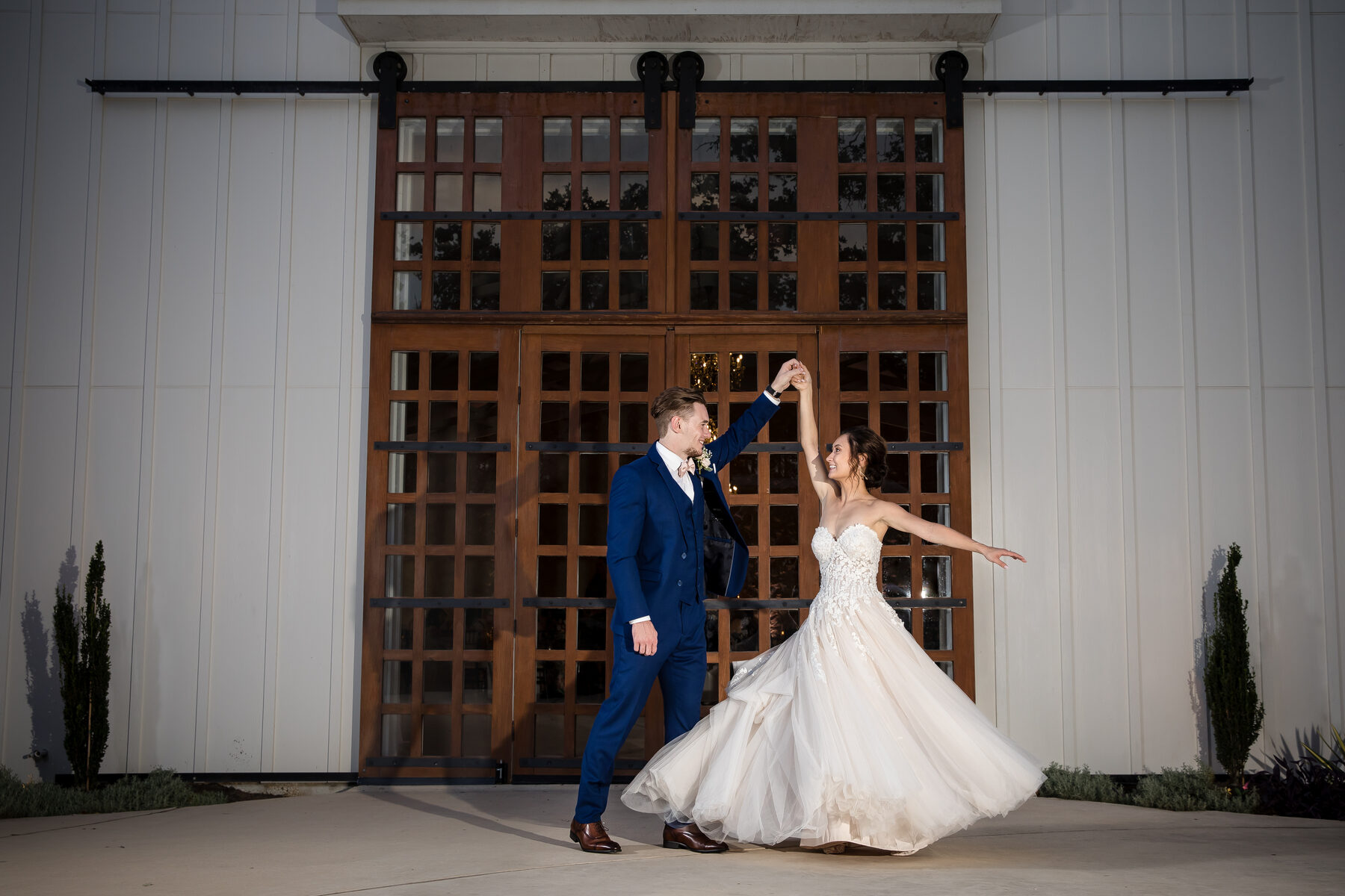 Couple dancing in front of large barn doors at night