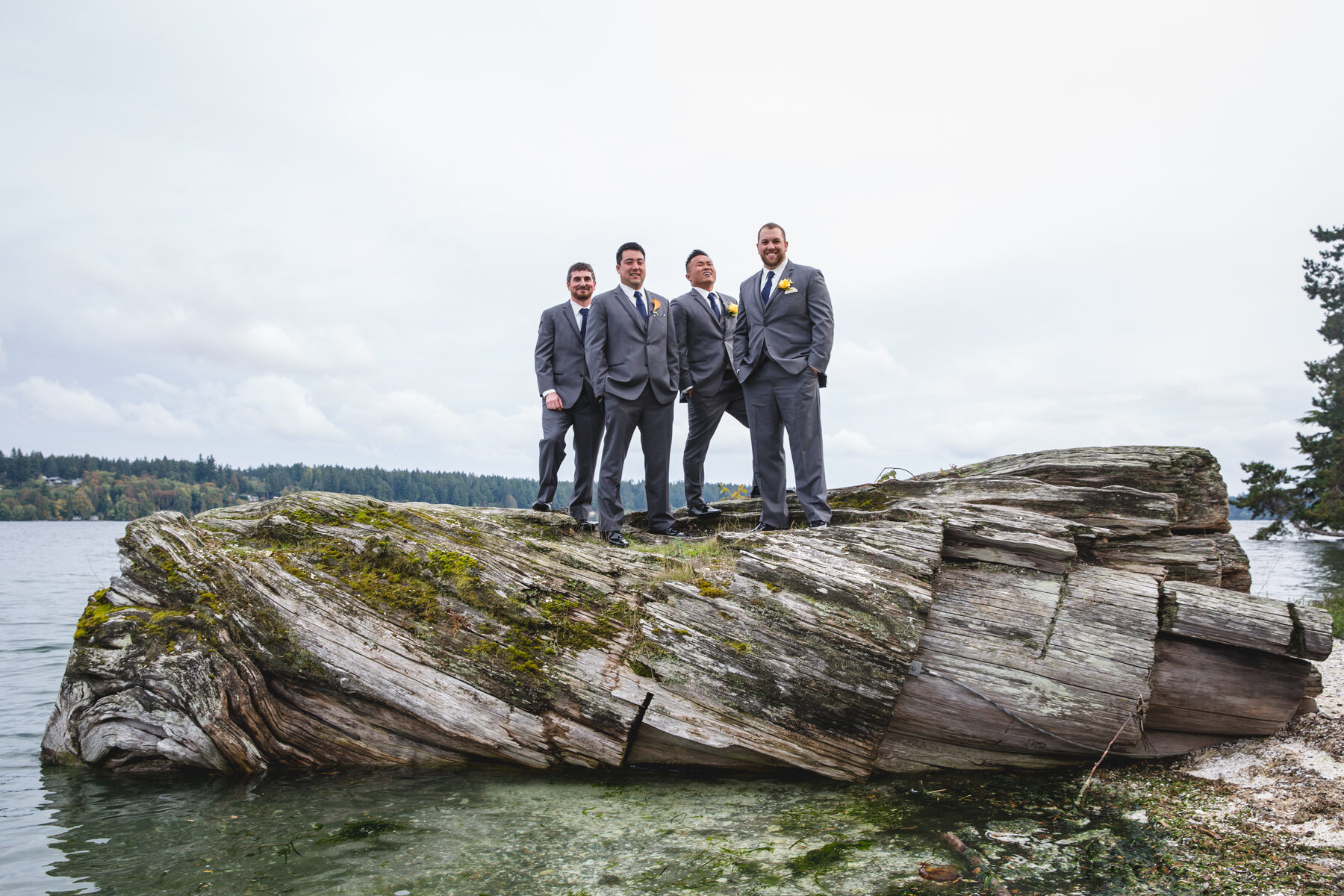 Groomsmen on driftwood log over water