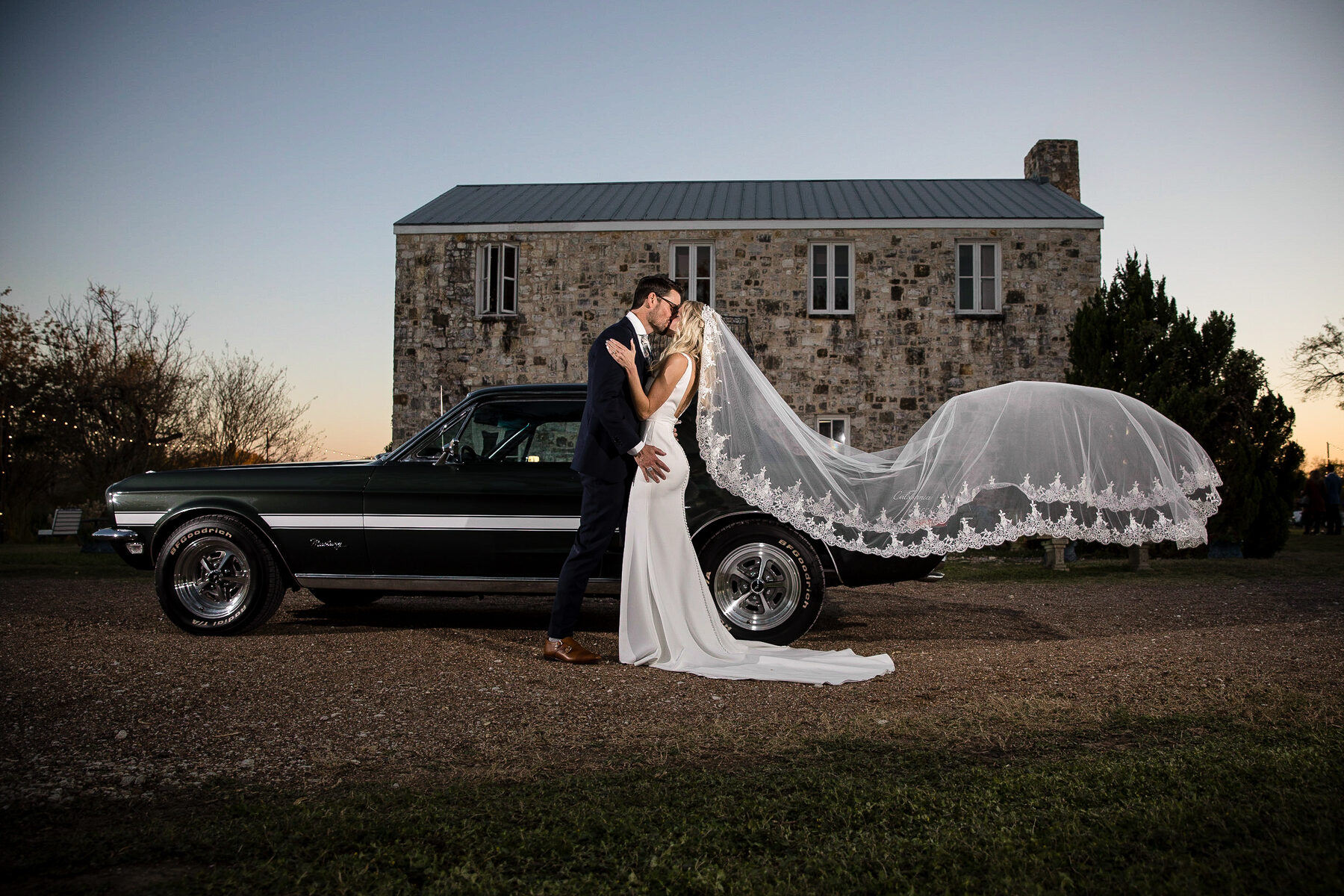 Couple at vintage car with sweeping veil