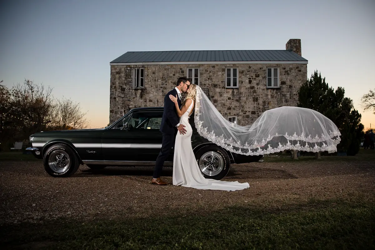 Couple at vintage car with sweeping veil