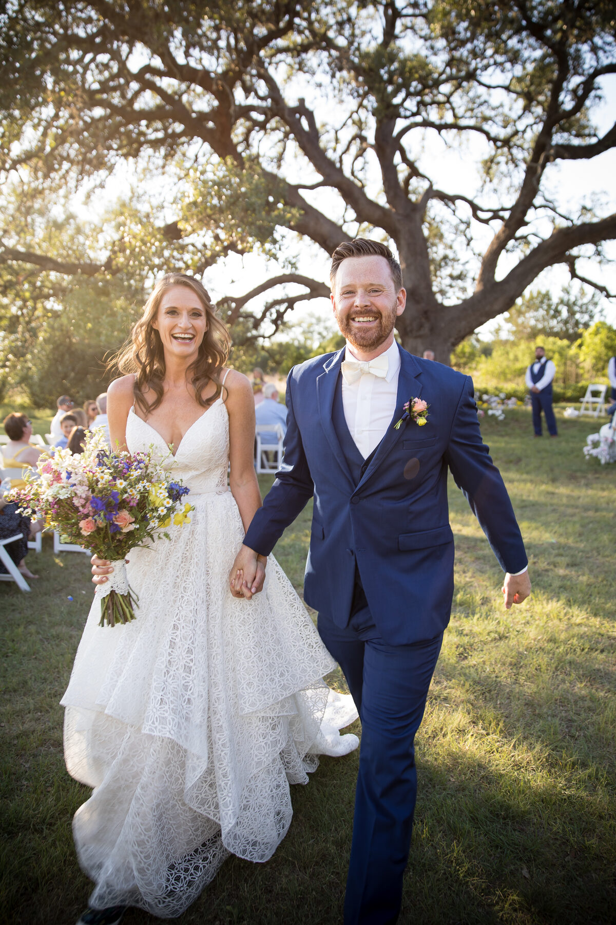 Newlyweds walking down the aisle under oak trees