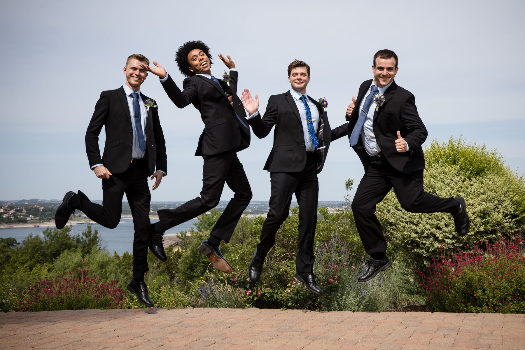 Groomsmen mid-jump in front of Hill Country