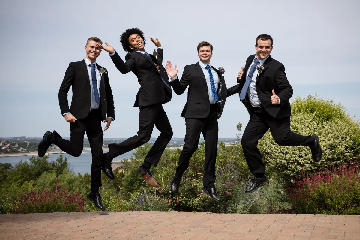Groomsmen mid-jump in front of Hill Country